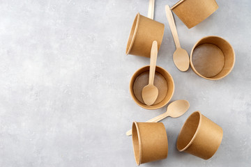 Top view of eco kraft paper cups and wooden spoons on grey background