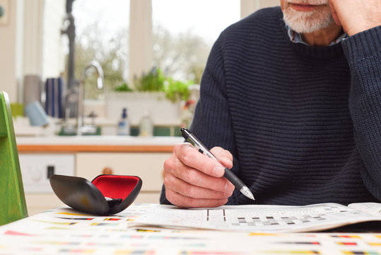 Mature man doing a crossword puzzle and relaxing at home during the day, indoor shot