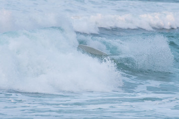 Surfer swallowed by a big wave on a beach on the north coast of Spain