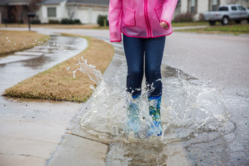 Girl jumping in big puddle on the street