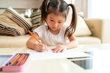 Naklejka premium Beautiful Asian girl doing homework in her living room at sweet home in a relaxing day, Asian Family Concept
