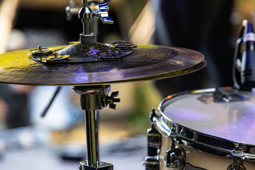 A detailed view of a percussion kit showing a hi hat cymbal fixed to a boom stand. with nuts and...