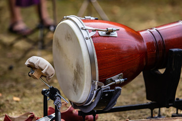 A close up shot of a traditional percussion drum instrument, against a blurry grass background in...