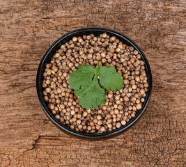 bowl of dried coriander seed on a wood background