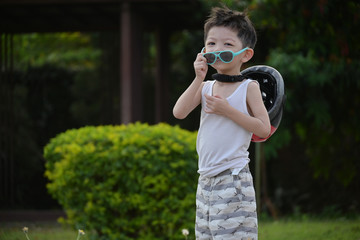 happy cute boy wear sunglasses and sport helmet playing bicycle exercise in the park