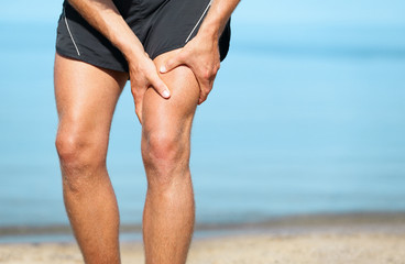 Sports injury muscle cramp pain fit runner man athlete holding painful thigh leg on outdoor summer jogging exercise. Fitness lifestyle. - obrazy, fototapety, plakaty