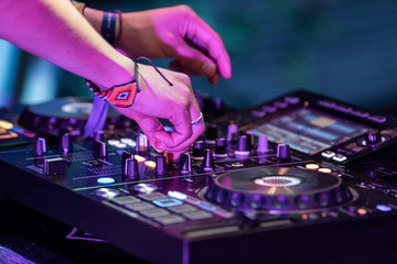 A close up shot on the hands of a music DJ using an electronic CDJ deck to perform a set during a...