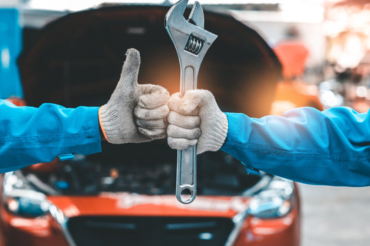 Car Mechanic Ready For Work. Auto Mechanic with Large Wrench in Hands. Ideas How to Fix the Problem.Male mechanics at the garage fixing a car.Closed up focus .
