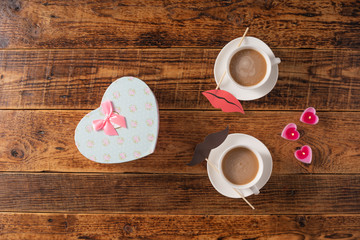 Valentine's Day celebration concept. A nice gift for your loved one. Coffee mugs and gift on a wooden table background. Copy space. Flat lay.