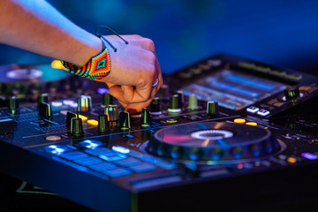 A selective focus shot on the hands of a modern electronic dance music DJ controlling a CDJ...