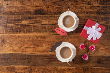 Valentine's Day celebration concept. A nice gift for your loved one. Coffee mugs and gift on a wooden table background. Copy space. Flat lay.