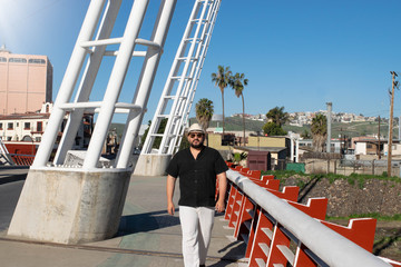  handsome mexican fat man with fedora style hat walking in the street wearing aviator glasses