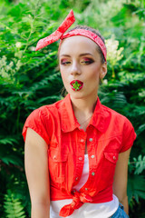 Beautiful young pin up girl with bright make up and fresh natural strawberry in mouth.