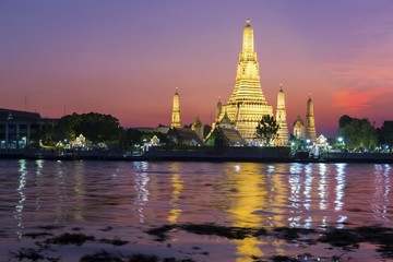 Fototapeta premium Dramatic Sunset Sky Colors over Wat Arun Temple or Temple of Dawn Buddhist Monument Reflected in Chao Phraya River in Bangkok, Thailand