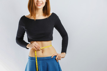 beautiful slender girl measuring waist meter