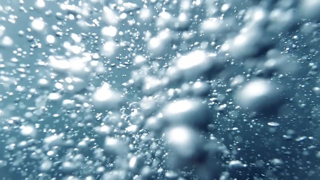 Closeup slow motion abstract video of lots of air bubbles floating up under water sea surface