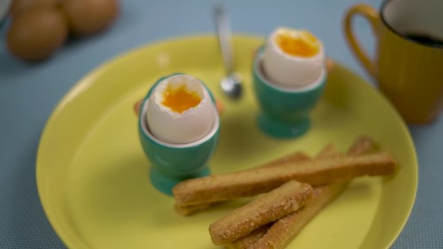 Pan movement on a plate with two a la coque eggs and toast on a green plate with coffee cup on the side