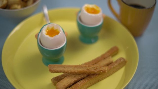 Two egg &agrave; la coque on a green plate with toast and a cup of coffee on the side