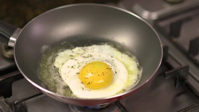 Seasoning being poured on top of delicious egg being fried in teflon frying pan