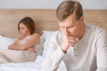 Sad couple after quarrel in bedroom
