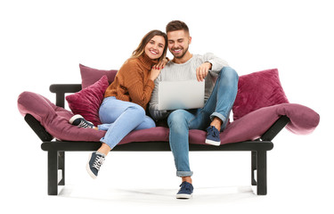 Young couple with laptop sitting on sofa against white background