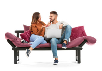 Obraz premium Young couple with laptop sitting on sofa against white background