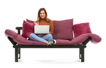 Young woman with laptop sitting on sofa against white background - Powered by Adobe