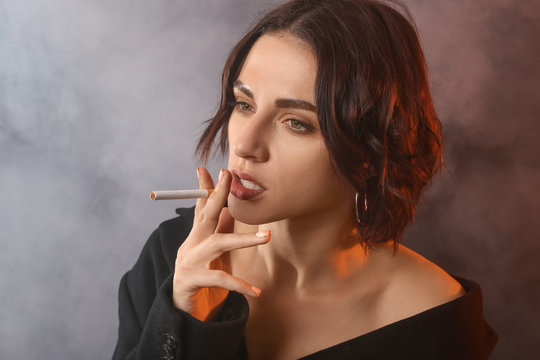 Portrait of fashionable smoking young woman on color background