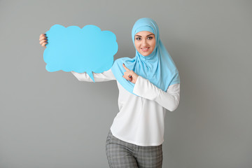 Beautiful Arab woman with blank speech bubble on grey background