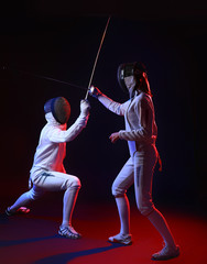 Toned photo of young fencers on dark background