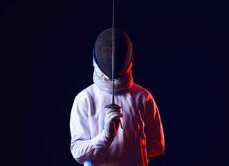 Toned photo of young fencer on dark background
