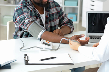 Female cardiologist examining male patient in clinic