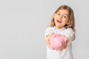 Cute girl with piggy bank on white background