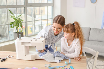 Little daughter helping her mother in tailor's workshop