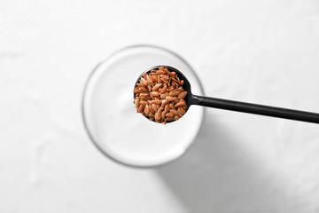 Spoon with flax seeds over glass with yogurt