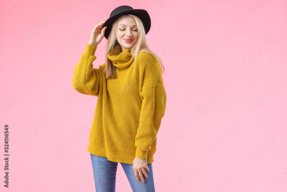 Wall mural Young woman in warm sweater on color background