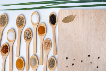 Various spices in wooden spoons, isolated background