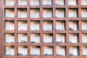 Aged wooden lattice on a white wall.
