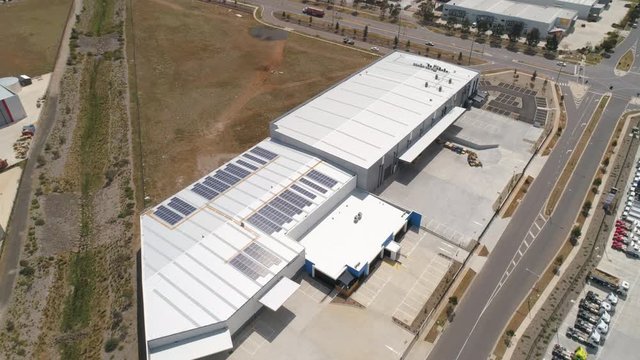 Solar panels installed on the roof of a large warehouse aerial