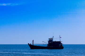 A fishing boat floats on Ko Lipe, Thailand on a day with clear blue sea and beautiful sunny skies.