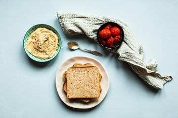 Baked tomatoes, hummus and bread. A beige towel and a spoon. Blue background. Top view horizontal image.