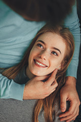 Fototapeta premium Charming caucasian girl with freckles and red beautiful red hair is lying on her boyfriend looking in his eyes