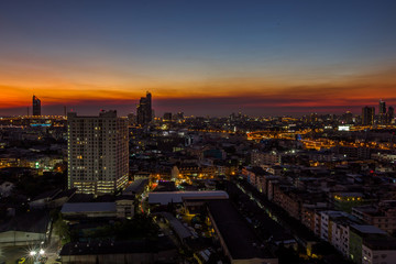 Naklejka premium The high angle background of the city view with the secret light of the evening, blurring of night lights, showing the distribution of condominiums, dense homes in the capital community