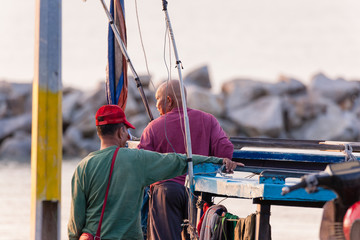 Closeup view of a fisherman's jetty and unidentified people during sunrise
