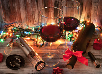 Electric corkscrew in steel gray. On a wooden background. Near the corkscrew aerotar, vacuum cork for wine. Two glass with wine and a bottle decorated with a red bow.