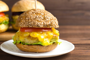 Vegetarian Burger with vegetable cutlet, pumpkin sauce, tomato on a dark wooden background. The concept of vegan, vegetarian, healthy food.
