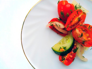 Vegetable salad of cucumbers and tomatoes with finely chopped dill on a white plate