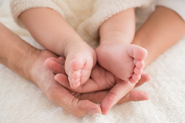 closeup newborn baby feet while the mother is carrying in home. baby feet in mother hands. mom and her Child. happy family concept. beautiful conceptual image of maternity.