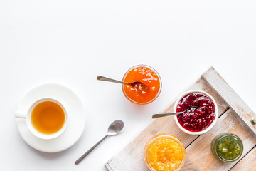 Fruit jam near tea on white kitchen desk copy space