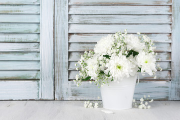 Fototapeta na wymiar White flowers bouquet against wooden shutters